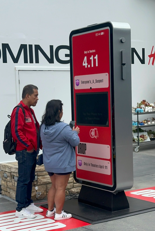 Two visitors using the Drop promotional kiosk at a Universal Studios event.